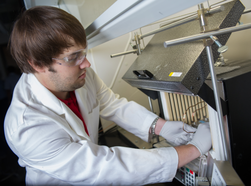 Georgia Tech researcher Andrew Brown places a finished hollow fibre metal-organic framework (MOF) membrane module into a membrane testing apparatus to measure its gas separation properties. (Credit: Rob Felt)