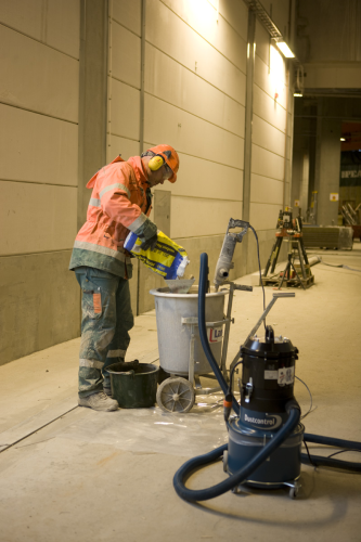 An industrial vacuum controlling dust during pouring.